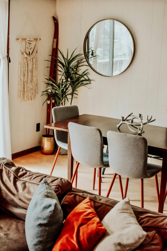 Cozy boho dining nook with round mirror, gray chairs, and warm-toned accents ideal for maximizing style in a small studio apartment in spring 2025


