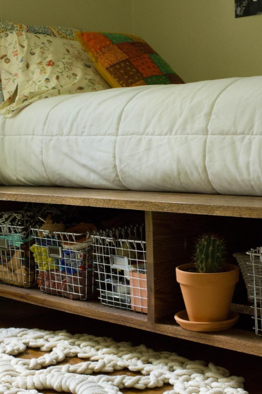 Compact underbed shelving with wire baskets and a small potted cactus, perfect for organizing essentials in a small studio apartment in Spring 2025.