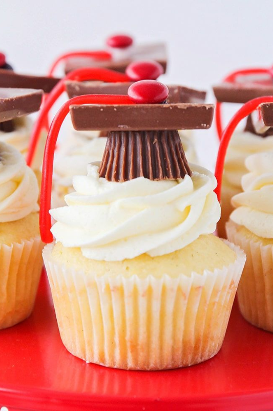 Vanilla graduation cupcakes topped with Reese’s and chocolate square candy caps, red licorice tassels, and red M&Ms — a fun and creative dessert idea for graduation parties.