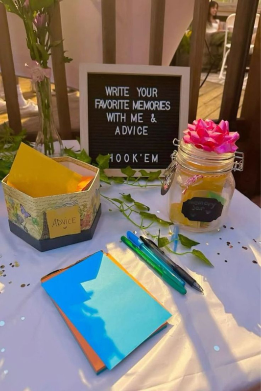 Graduation party table setup with memory jar, advice cards, colorful pens, and a letterboard sign asking guests to share favorite memories and advice for the graduate.