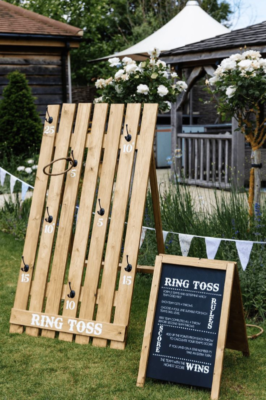 Outdoor graduation party ring toss game setup with wooden scoring board, hook points, and chalkboard instructions — a fun lawn activity for guests of all ages.