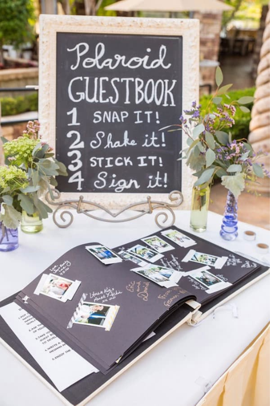 Creative Polaroid guestbook station at a graduation party with chalkboard instructions, photo album, instant prints, and floral table decor.