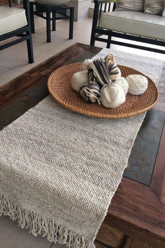 rustic coffee table with a textured table runner, round wicker tray filled with yarn balls, creating a cozy and natural living room vibe

