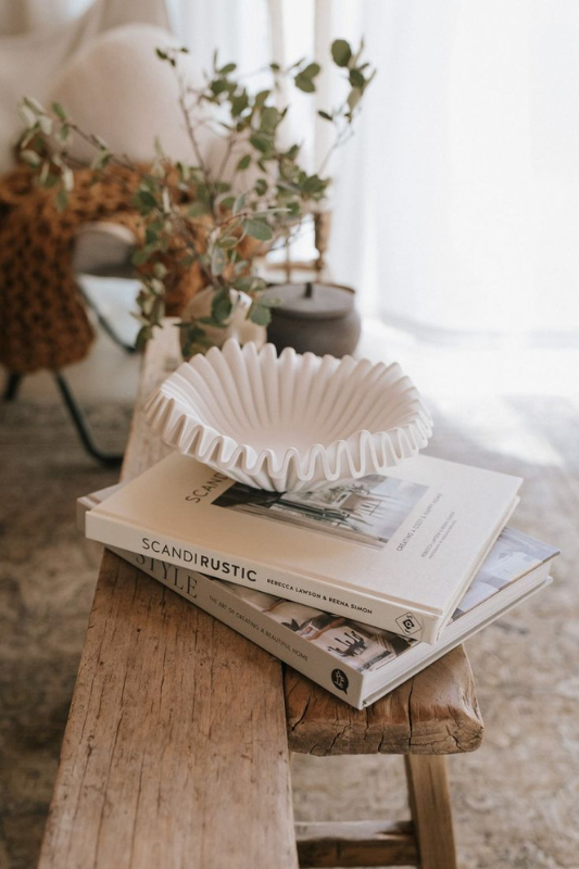 Scandinavian-inspired coffee table styling with a ruffled ceramic bowl, neutral decor books, and organic textures for a cozy minimalist vibe