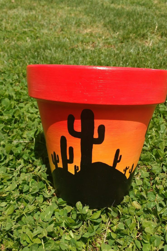 Hand-painted terracotta pot with bold red and orange sunset gradient and black cactus silhouettes. Ideal for desert-inspired decor, this southwestern-style planter adds warmth and artistic flair to gardens or balconies.