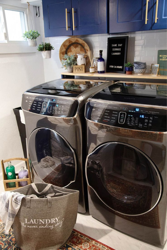 Classic white laundry room with bold patterned floor tiles, white cabinetry, front-load washer and dryer, and stylish woven baskets for a neat, functional space. 