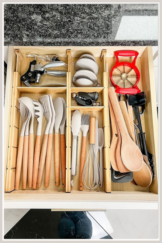 Top-down view of a kitchen drawer with a structured cutlery organizer separating spoons, forks, knives, and tools, showcasing smart kitchen drawer organization for everyday use. 
