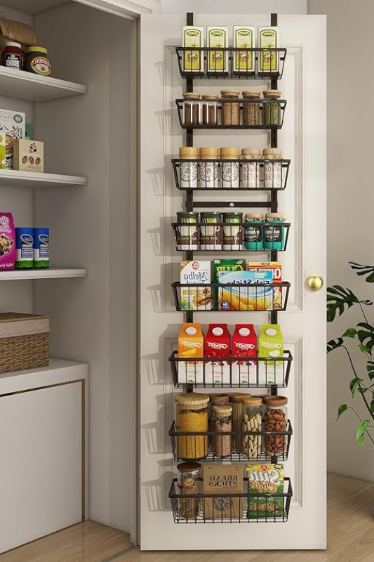 Black metal over-the-door pantry organizer with multiple deep wire baskets storing spices, dry goods, and breakfast essentials, ideal for renters or small kitchen spaces with limited cabinet room. 