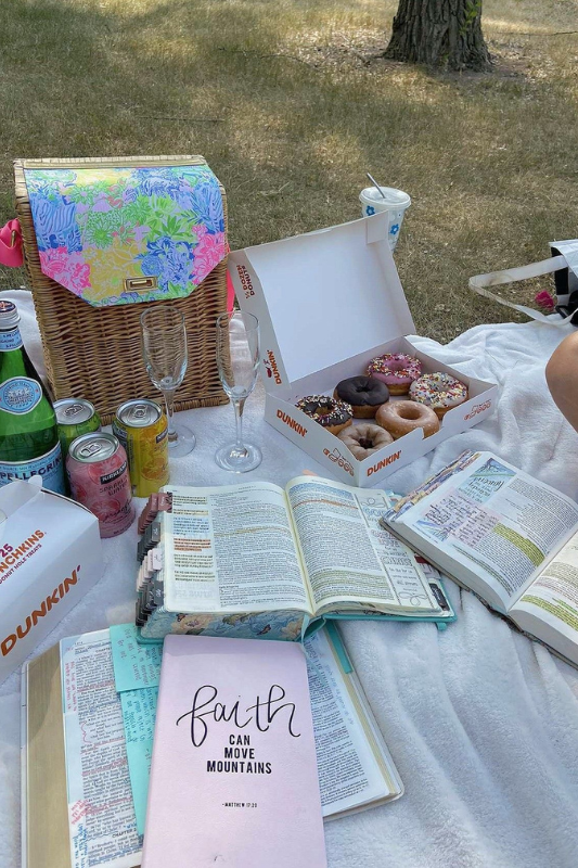 Outdoor picnic setup featuring Bibles, devotionals, Dunkin’ donuts, and sparkling water for a relaxing faith-based picnic with friends or solo.