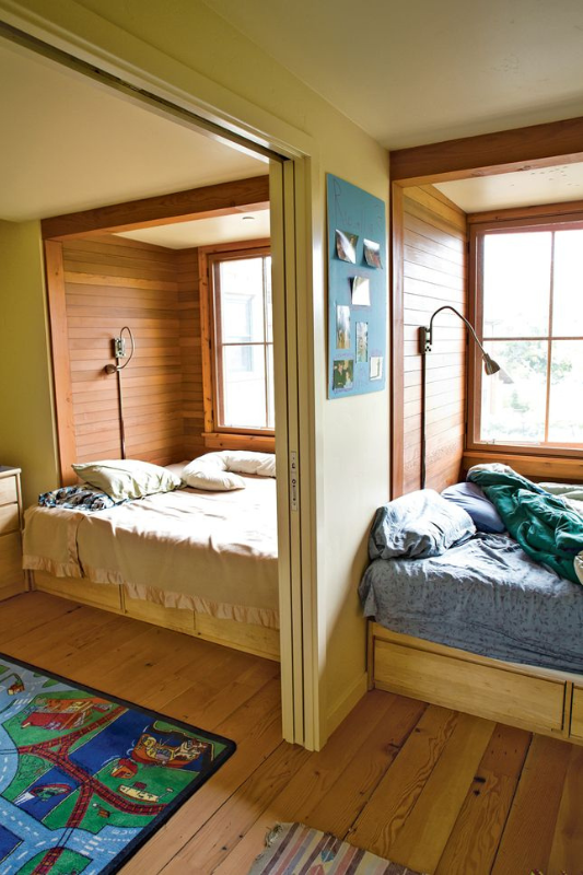 Two cozy nook-style bedrooms divided by a sliding door, each with wood-paneled walls and large windows.