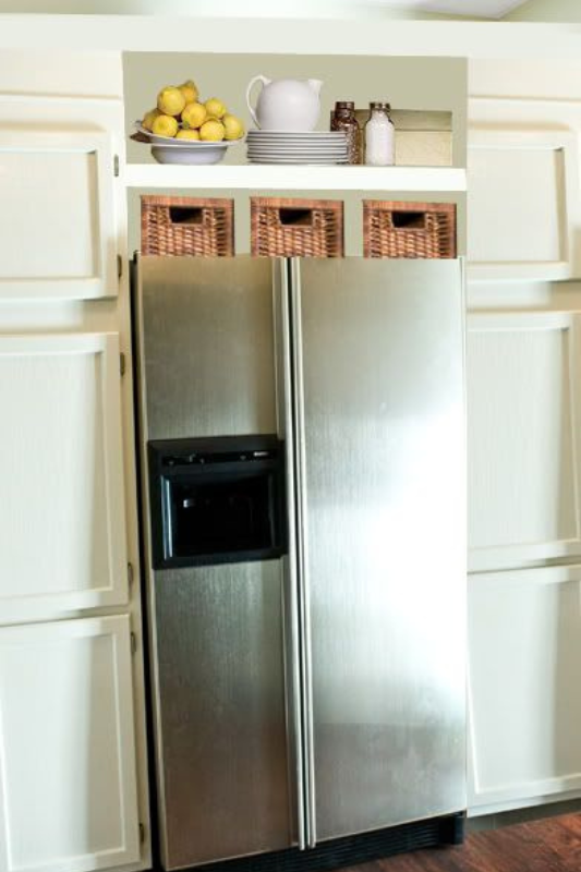 Built-in fridge nook with woven baskets, white pitcher, and bowl of lemons on top shelf for bright and tidy kitchen storage