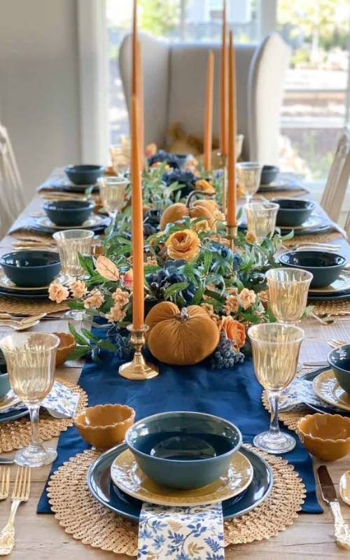 Fall tablescape with navy and amber accents, velvet pumpkins, and floral centerpiece.
