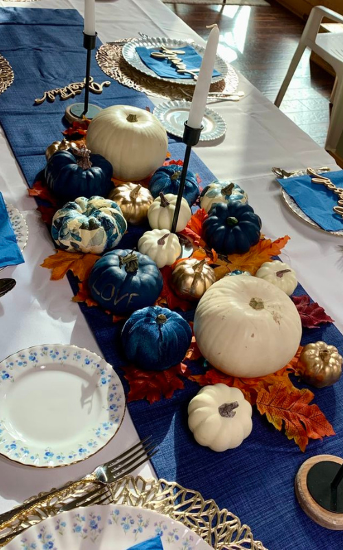 Luxe fall table with velvet pumpkins, gold accents, navy runner, and candlelight.