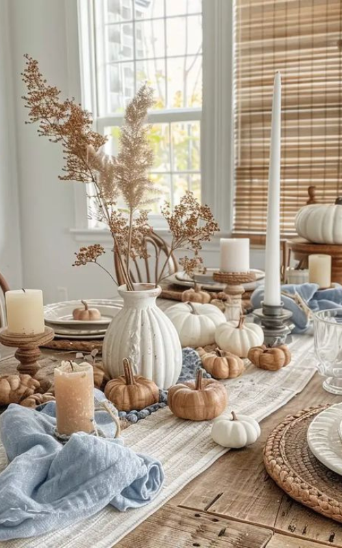 Bohemian fall dining table with pumpkins, candles, soft blue napkins, and rustic linen table runner.
